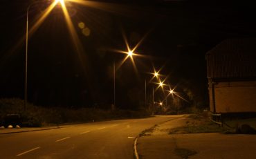 Gatubelysning som lyser i mörkret längs med en gata