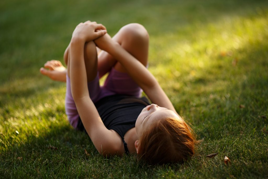 Flicka ligger på gräsmatta