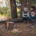 Pojke tillsammans med vuxen sitter och pratar i skogen