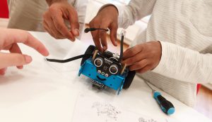En bild på händer tillhörande barns som bygger en robot.